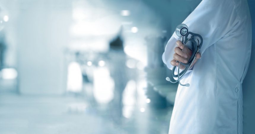 Doctor with stethoscope in hand on hospital background, medical เจ็บป่วยมีประกัน ให้คลินิกประกัน SMC ช่วยดูแล